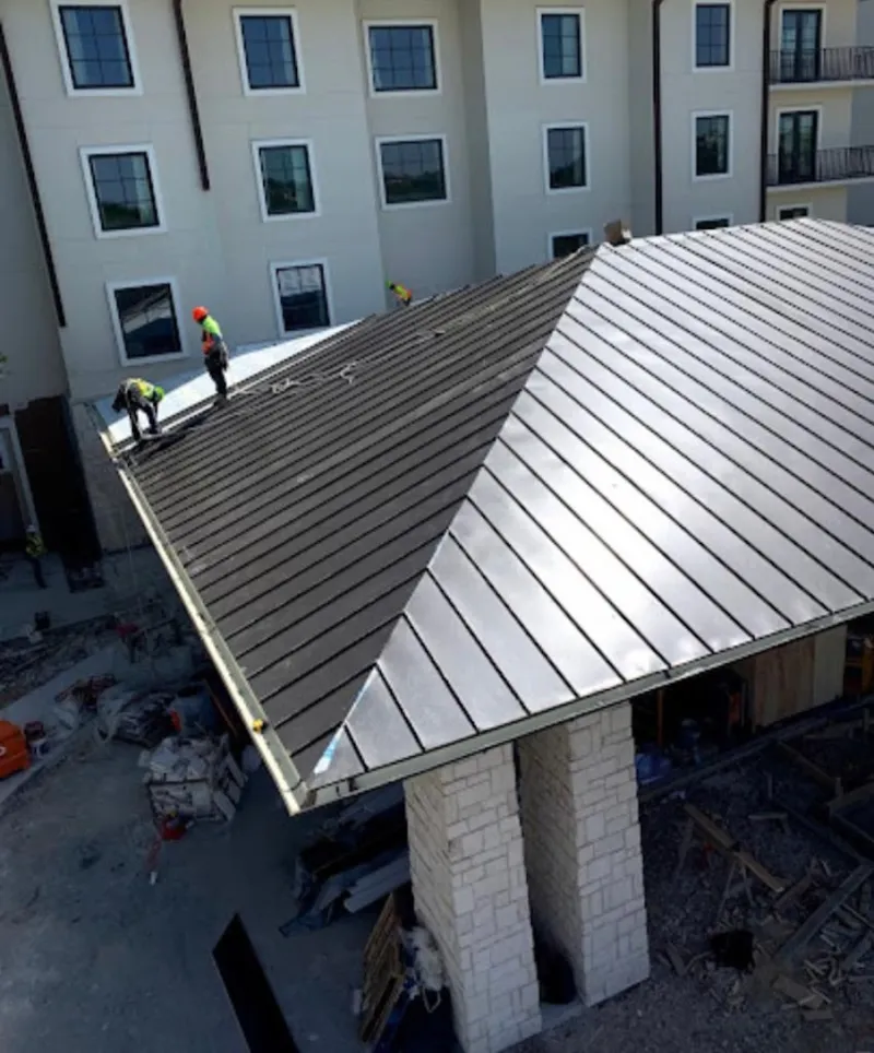 Crew installing standing seam metal roof panels on a commercial project in Hooksett